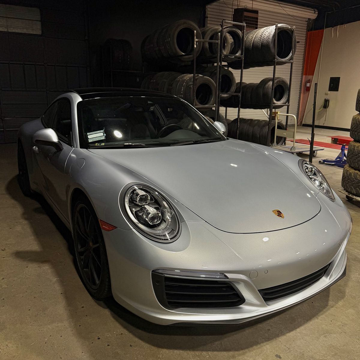 Porsche 911 in the shop with the tire inventory rack behind it