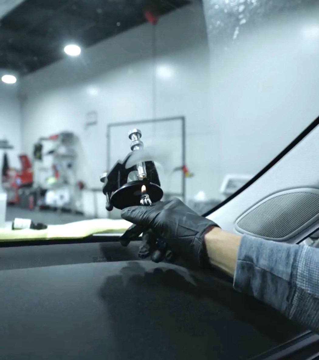 Technician repairing a rock chip in a windshield